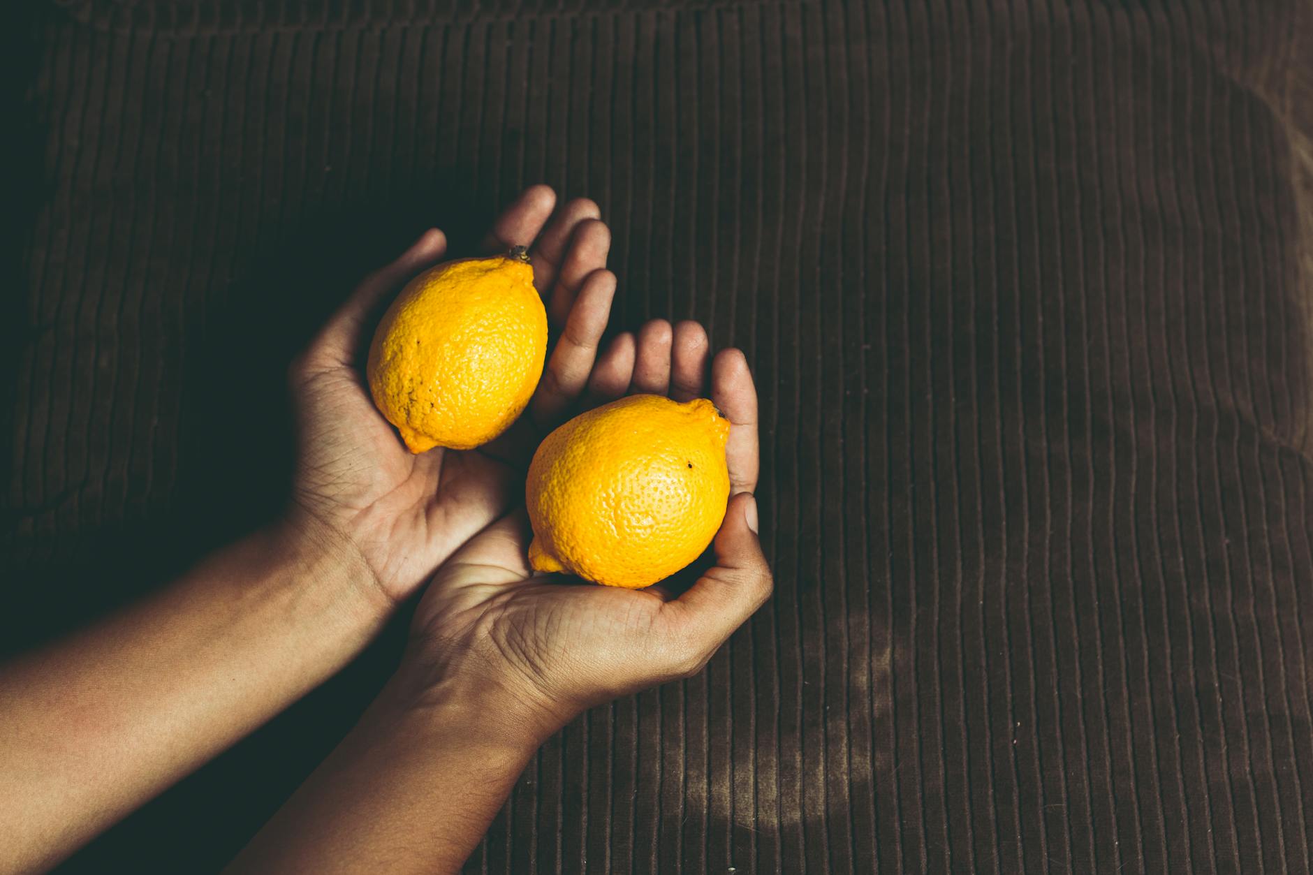 Two fresh lemons held in cupped hands, symbolizing gentle yet effective stimulation