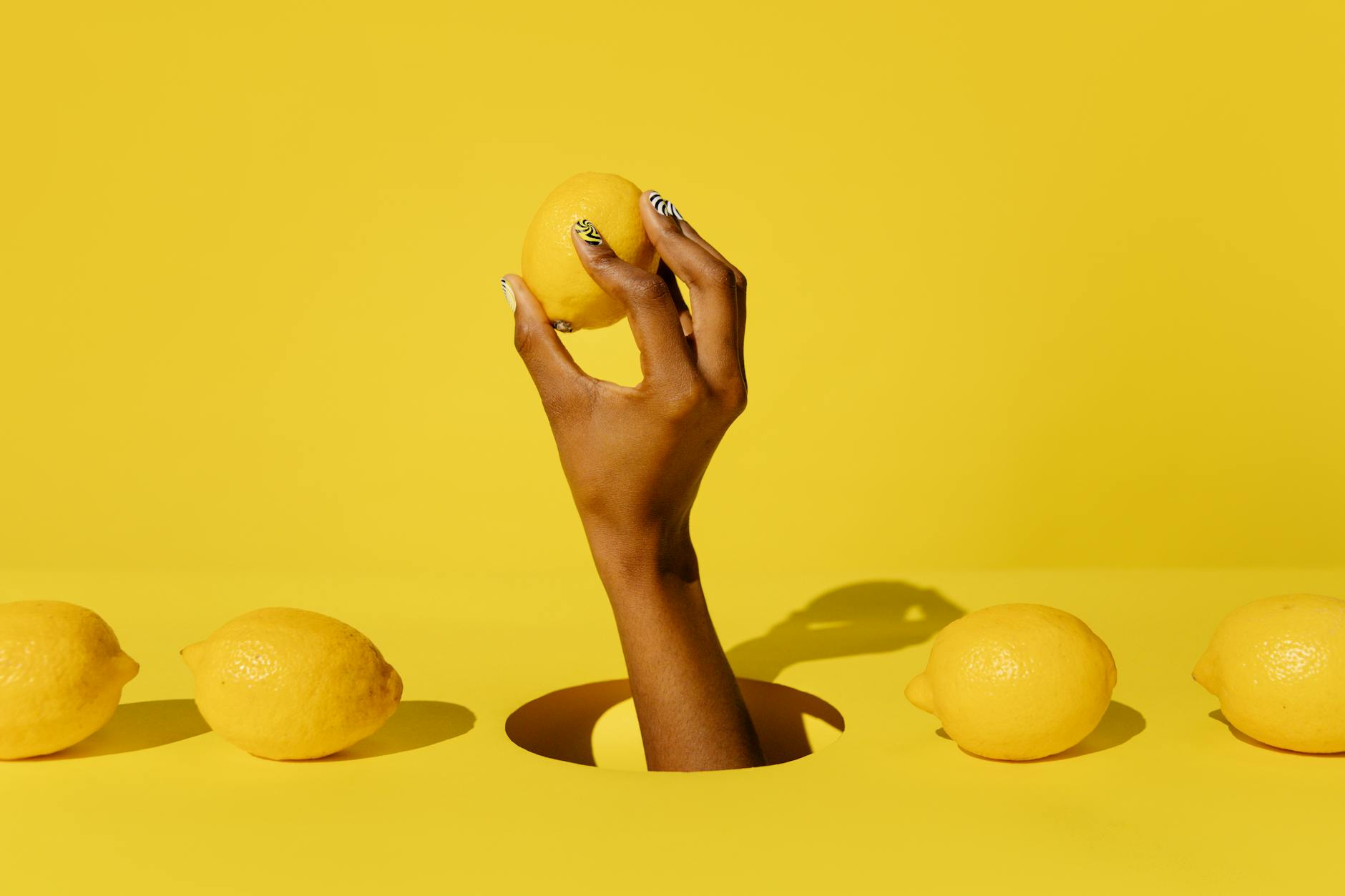 A fresh lemon held in hand against a bright yellow background, symbolizing renewal and natural healing