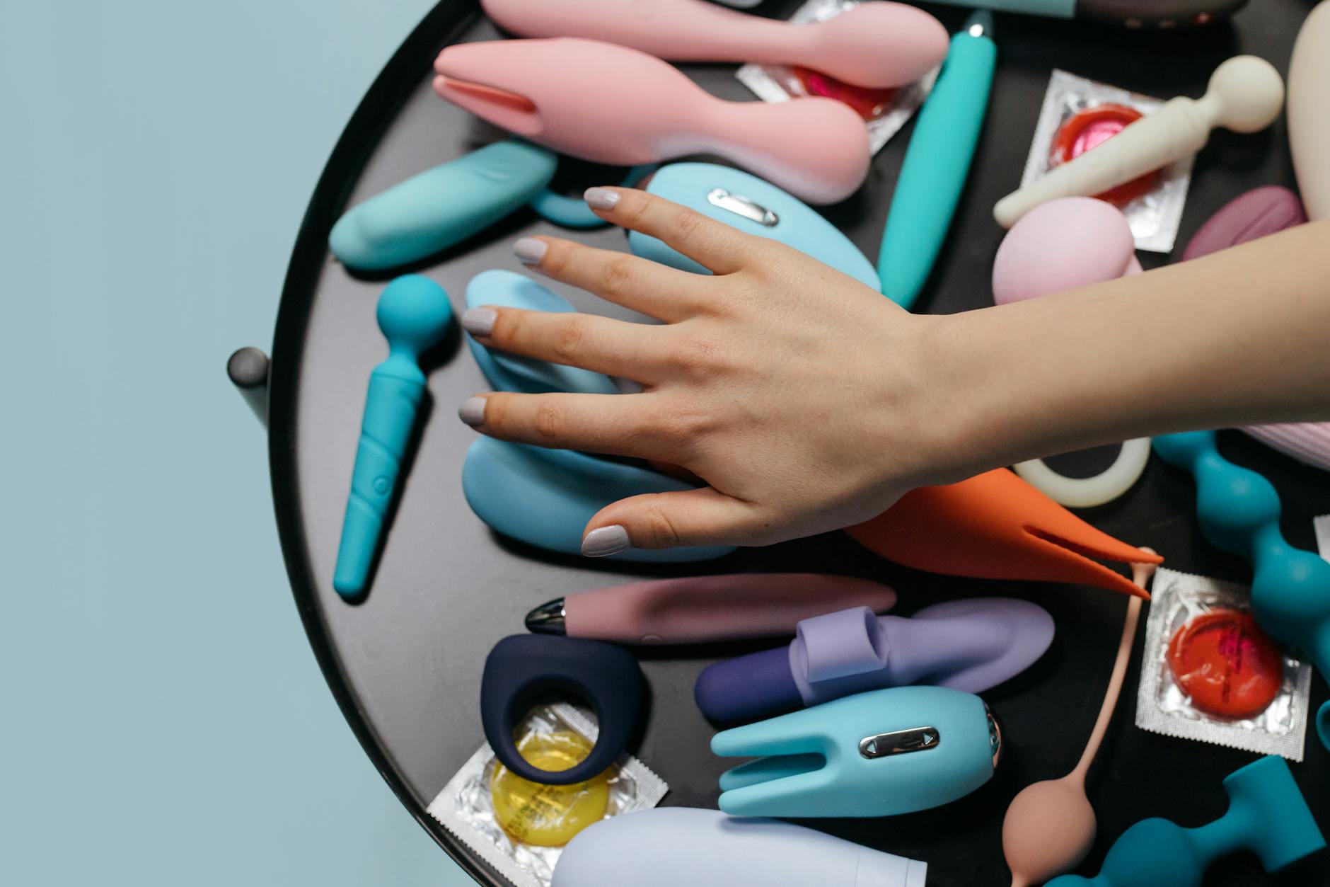 Woman holding blue and pink silicone vibrators