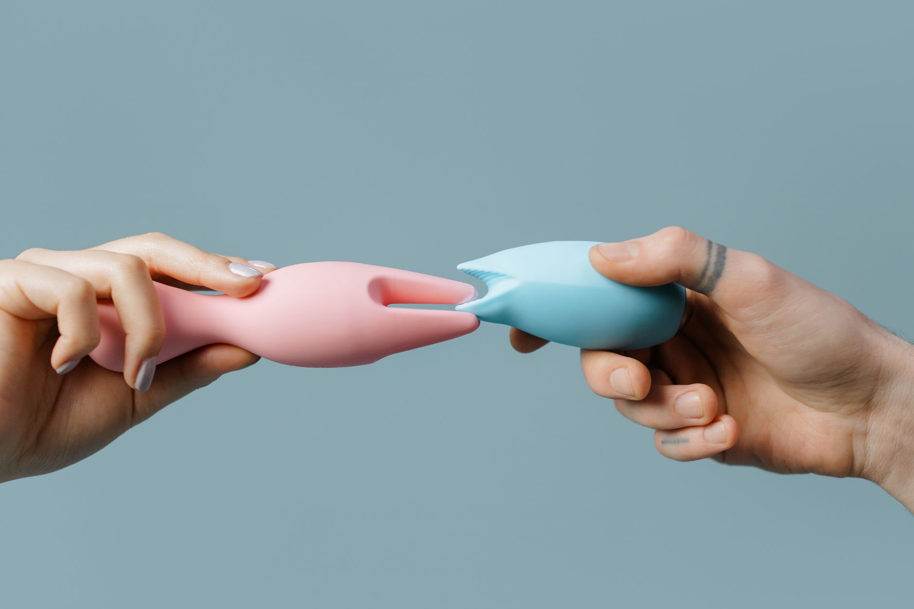 Woman with glasses holding silicone vibrators in a contemplative, grounded posture