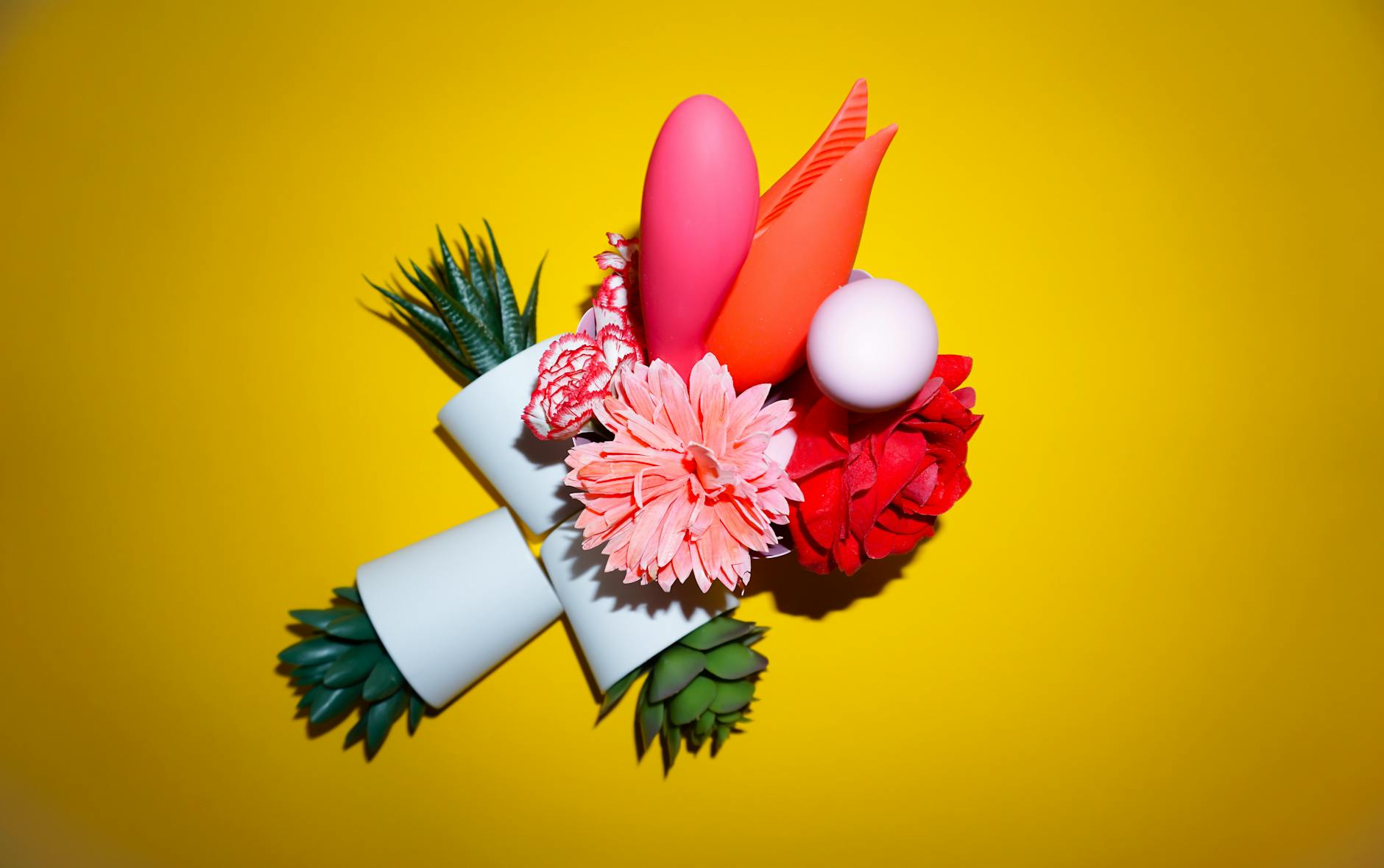 Two hands holding pink and blue silicone vibrators against a pastel background, representing accessible pleasure at any age.